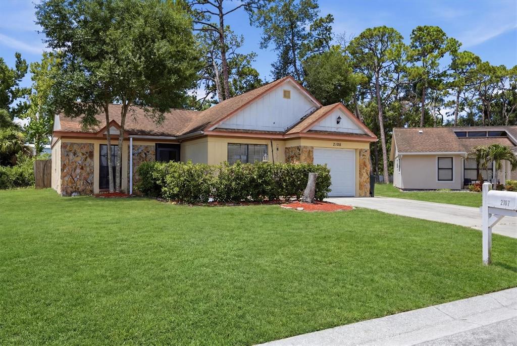 A single-story house with a stone facade, tan siding, and a white garage door — 2108 E 56TH AVENUE TERRACE, BRADENTON, FL