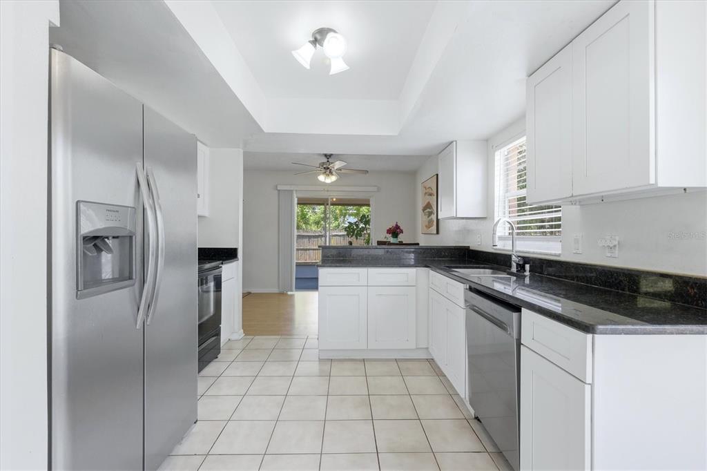 A kitchen with white cabinets, black countertops, stainless steel appliances, and tile flooring — 2108 E 56TH AVENUE TERRACE, BRADENTON, FL