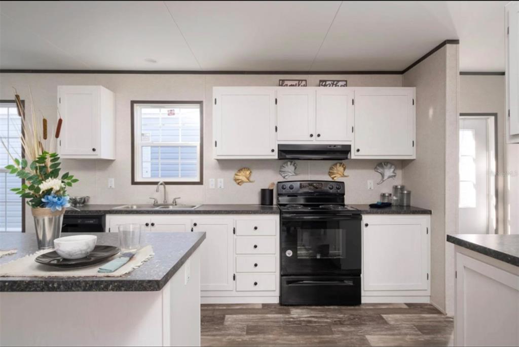 A kitchen features white cabinets, black appliances, a dark countertop, and a center island — 311 CHESSER MONROE ROAD, HAWTHORNE, FL