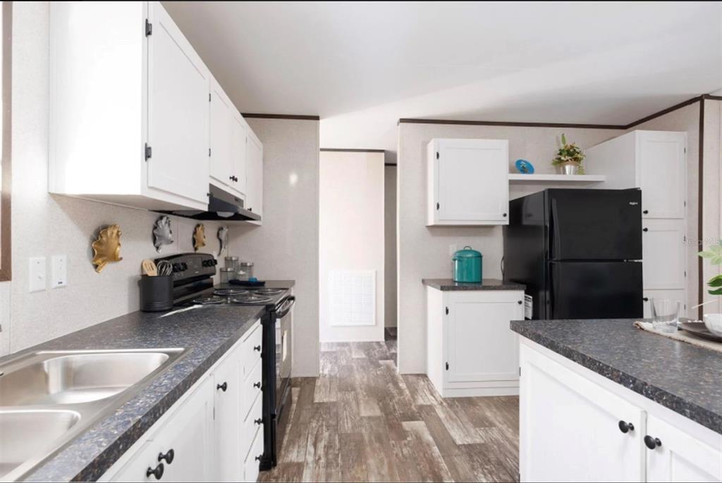 A kitchen features white cabinets, dark countertops, black appliances, and wood-look flooring — 311 CHESSER MONROE ROAD, HAWTHORNE, FL