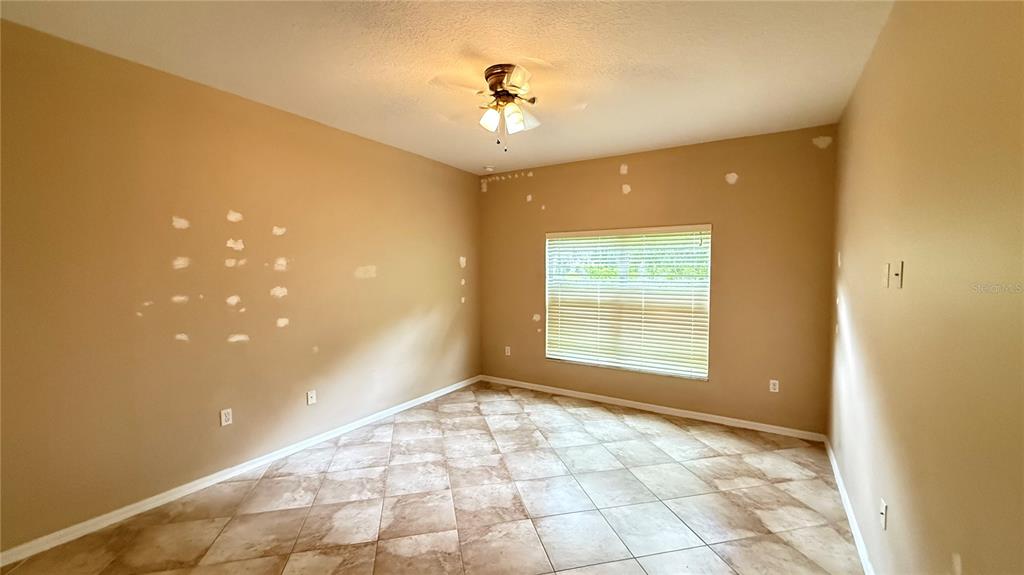 An empty room with tan walls, tiled floors, a ceiling fan, and a window with blinds — 3559 SUNSET ISLES BOULEVARD, KISSIMMEE, FL