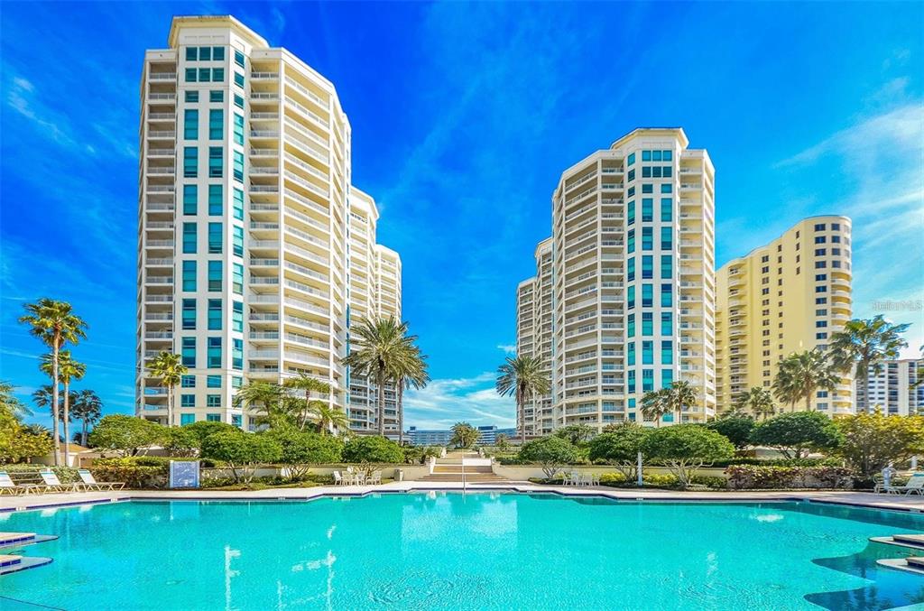 A large swimming pool sits in front of several tall, multi-story residential apartment buildings — 1180 GULF BOULEVARD UNIT 1703, CLEARWATER BEACH, FL