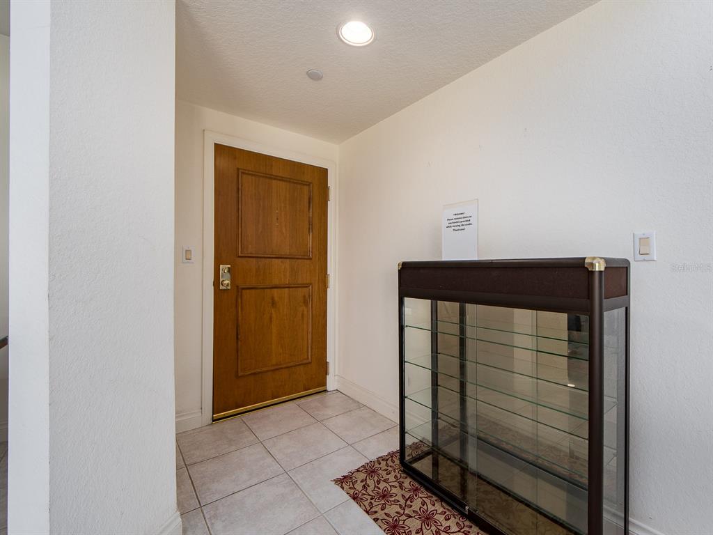 An entryway features a wooden door, tiled flooring, and a glass display cabinet — 1180 GULF BOULEVARD UNIT 1703, CLEARWATER BEACH, FL
