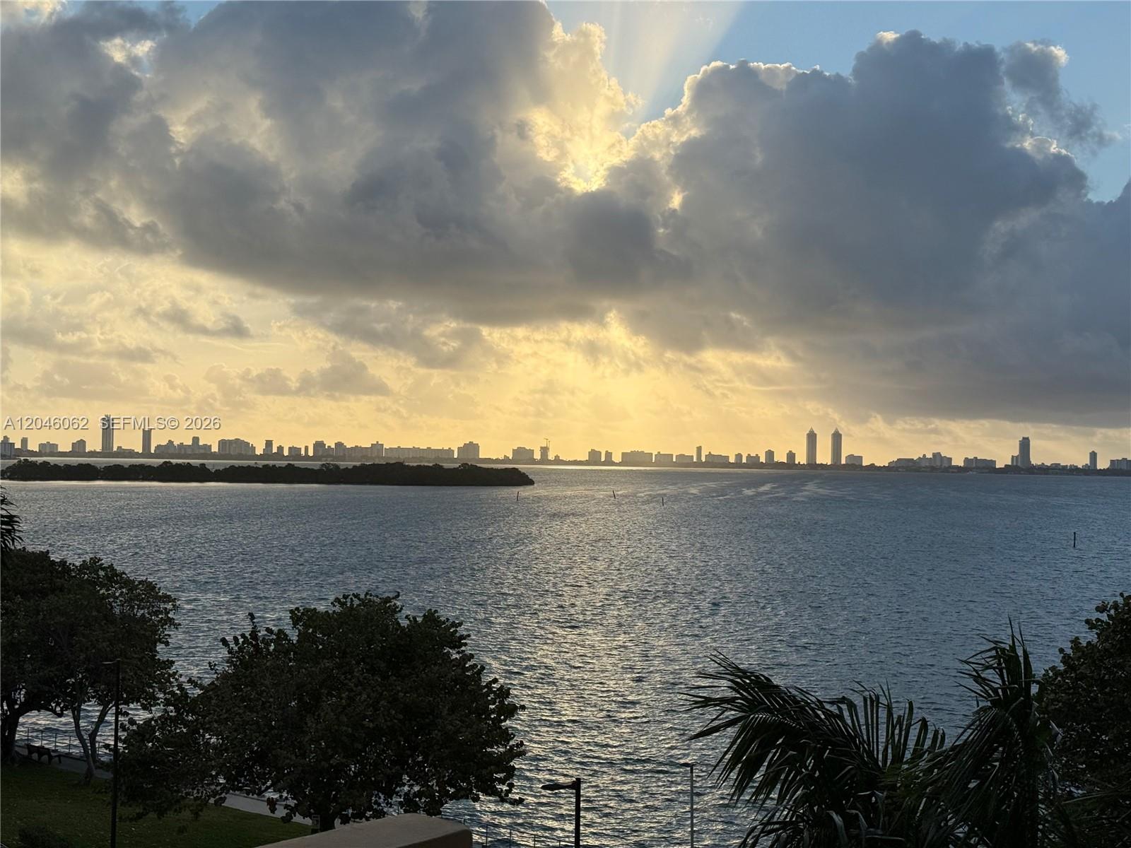 A view of a bay and city skyline under a cloudy, sunlit sky — 880 NE 69th St # 5Q, Miami FL 33138, MIAMI, FL