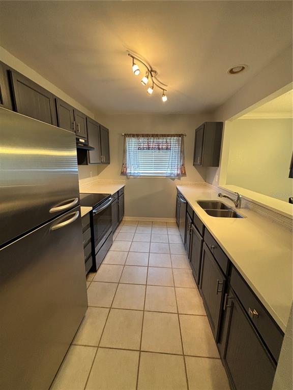 A galley kitchen features dark cabinets, stainless steel appliances, white countertops, and tiled flooring — 1968 TOUCAN WAY UNIT 1404, SARASOTA, FL