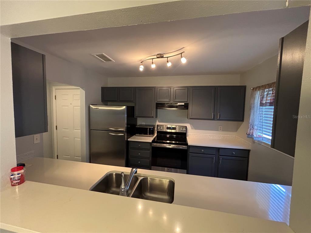 A kitchen features dark gray cabinets, stainless steel appliances, and a white countertop — 1968 TOUCAN WAY UNIT 1404, SARASOTA, FL