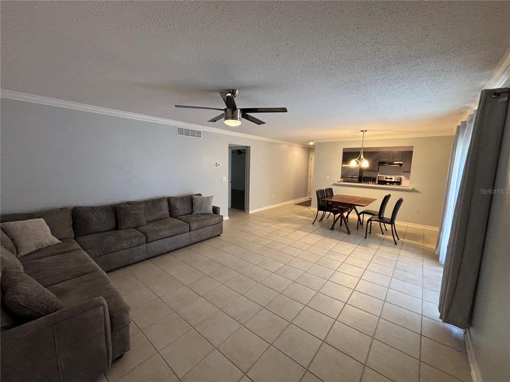 A living and dining area with tile floors, a ceiling fan, and a sectional sofa — 1968 TOUCAN WAY UNIT 1404, SARASOTA, FL
