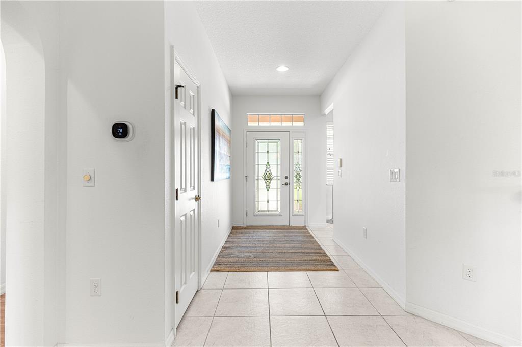 A bright entryway features white walls, tiled flooring, a front door with glass inserts, and a rug — 9317 SW 94TH LOOP, OCALA, FL