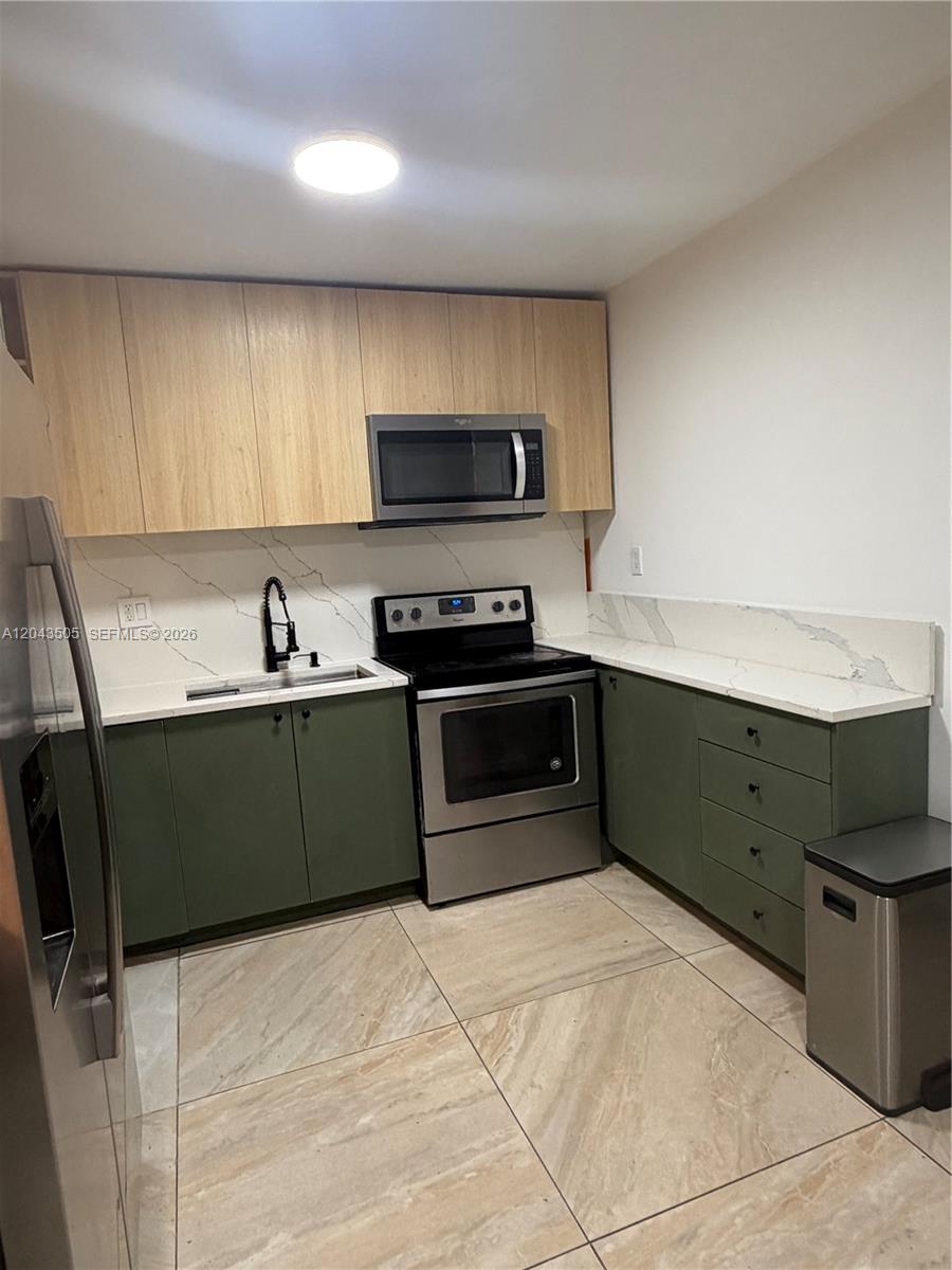 A kitchen features green lower cabinets, light wood upper cabinets, and white marble-patterned countertops — 1955 Wiley St # a, Hollywood FL 33020, HOLLYWOOD, FL