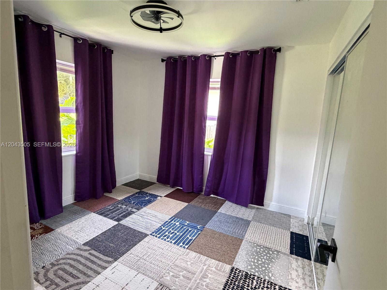 A bedroom features purple curtains, white walls, and a multi-patterned patchwork carpet — 1955 Wiley St # a, Hollywood FL 33020, HOLLYWOOD, FL