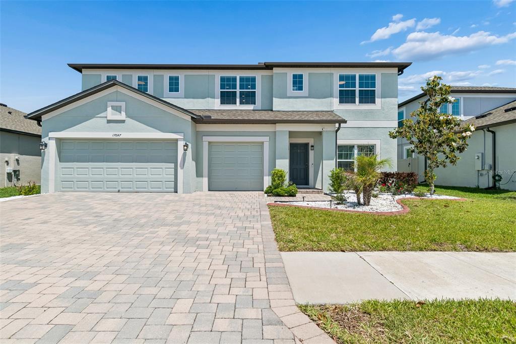 A two-story house with a light blue stucco exterior, a paved driveway, and two garages — 17647 CORTES CREEK BOULEVARD, SPRING HILL, FL