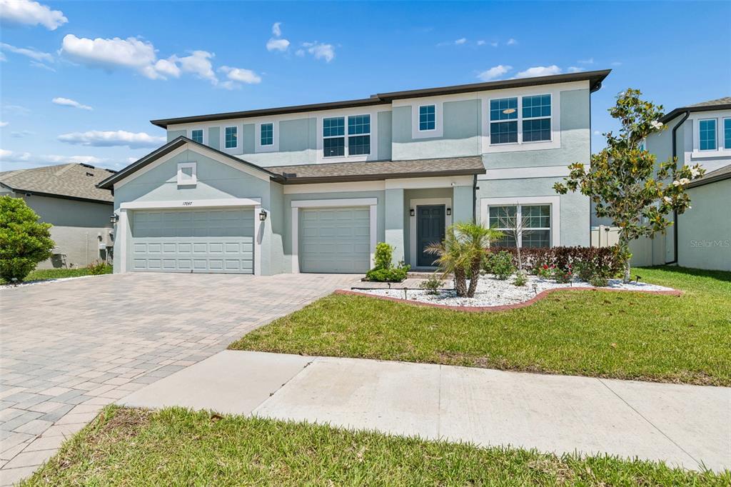 A two-story house with a light blue exterior, three-car garage, and a paved driveway — 17647 CORTES CREEK BOULEVARD, SPRING HILL, FL