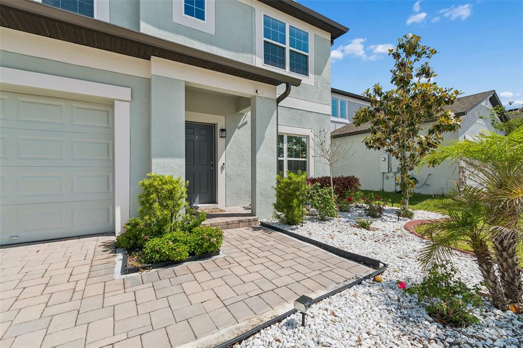 A light-colored two-story house features a paved walkway, a garage, and a landscaped front yard — 17647 CORTES CREEK BOULEVARD, SPRING HILL, FL