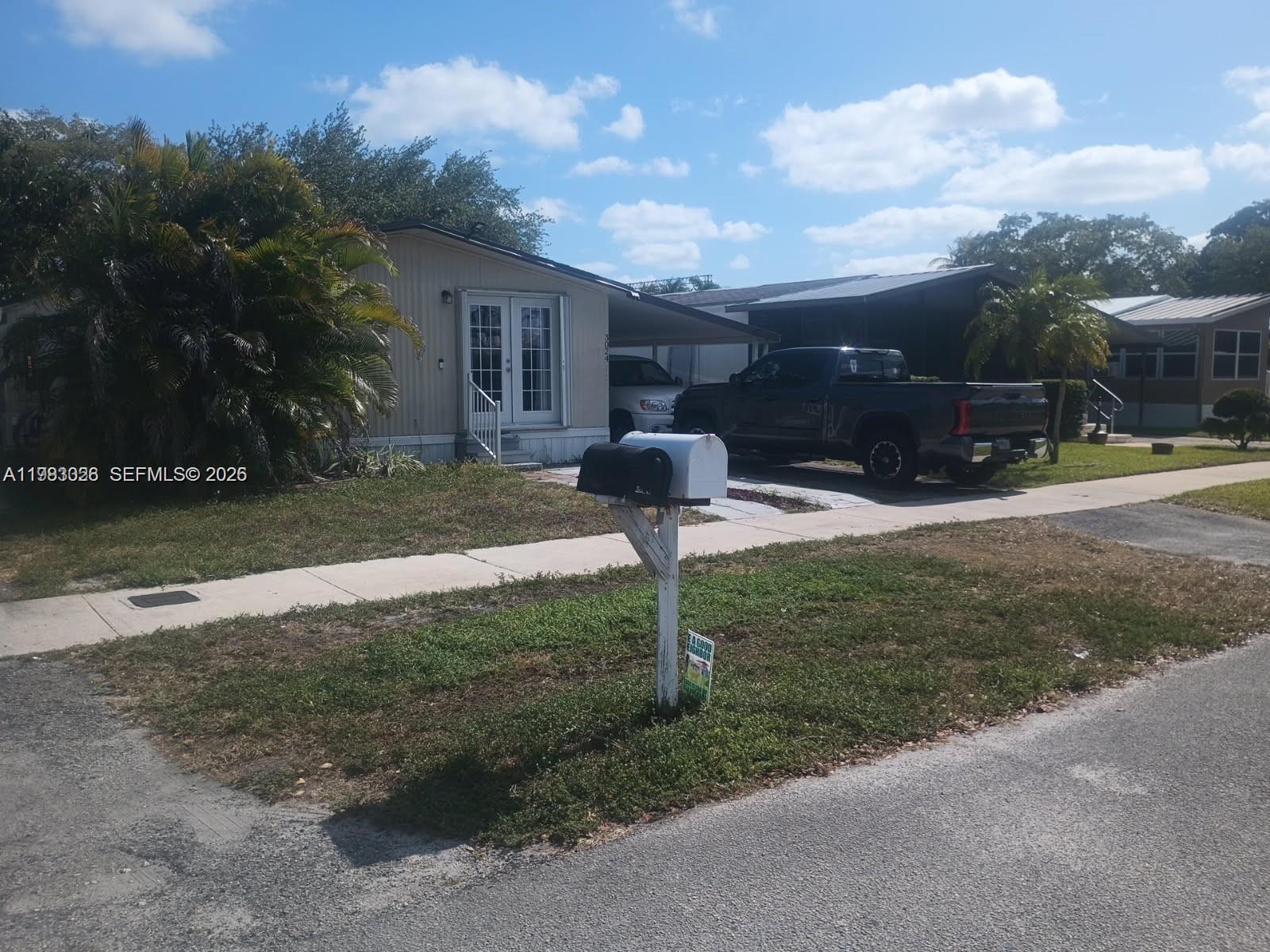 A single-story manufactured home with a carport, a dark pickup truck, and a front mailbox — 3024 SW 51st St, Dania Beach FL 33312, DANIA BEACH, FL