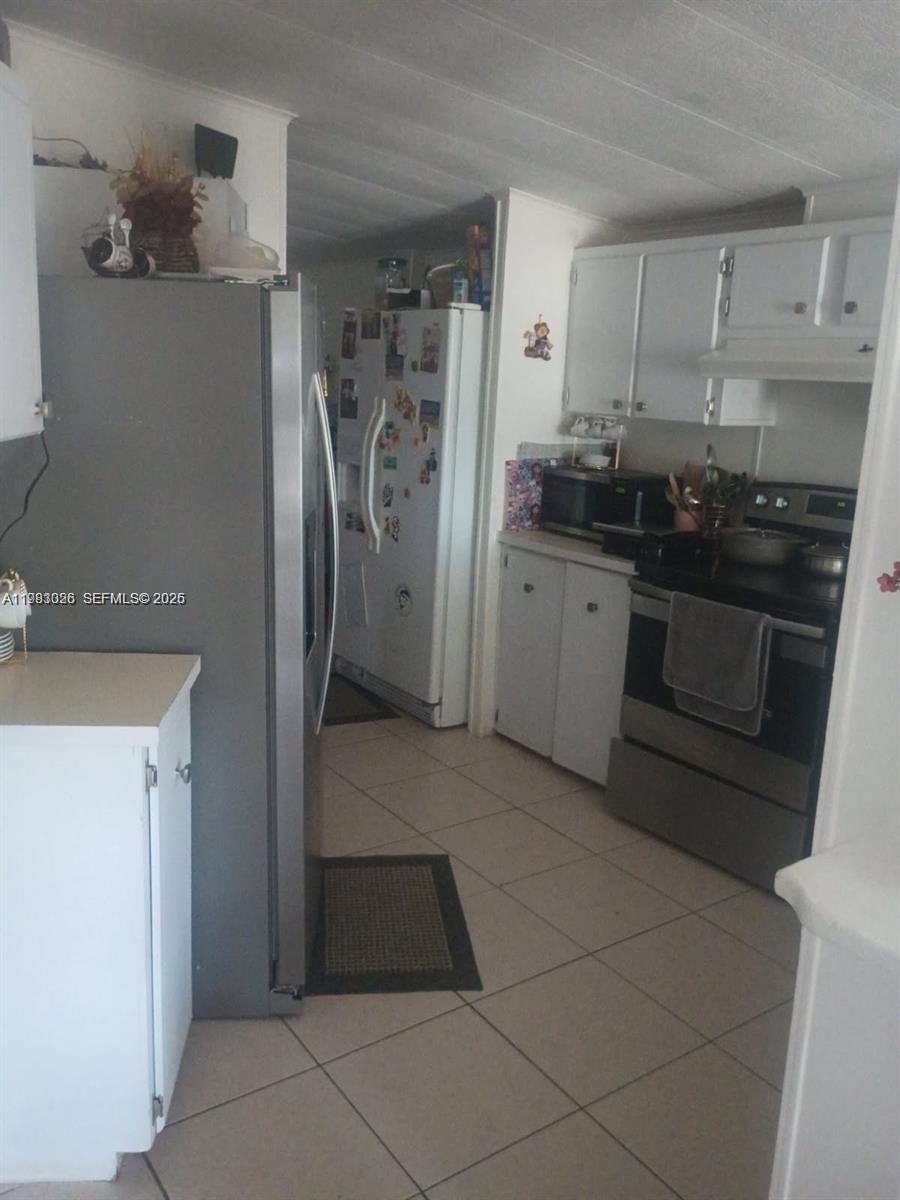 A kitchen features white cabinets, a stainless steel refrigerator, and a stainless steel stove — 3024 SW 51st St, Dania Beach FL 33312, DANIA BEACH, FL