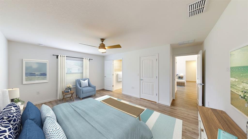 A bedroom features a bed, a blue armchair, light wood flooring, and two open doorways — 1620 GERANIUM AVENUE, NORTH PORT, FL
