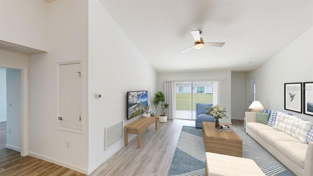 A living room features light wood flooring, a vaulted ceiling, a ceiling fan, and sliding doors — 1620 GERANIUM AVENUE, NORTH PORT, FL