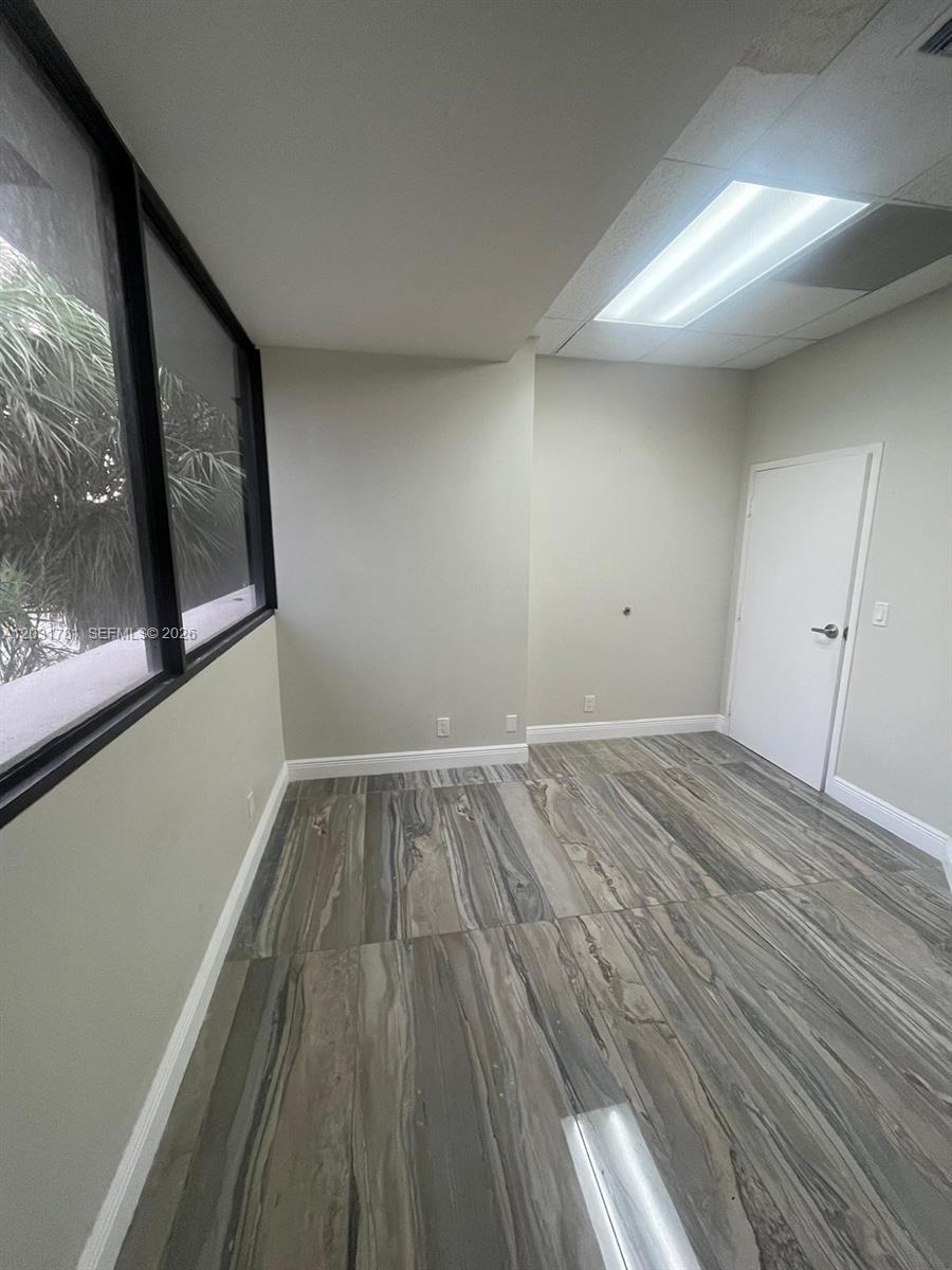 An empty office space features large windows, light-colored walls, and patterned tile flooring — 6101 W Atlantic Blvd # 208, Margate FL 33063, MARGATE, FL