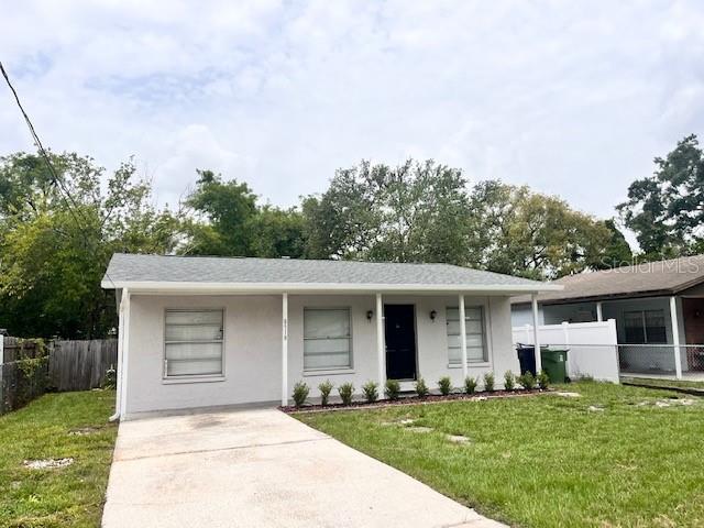 A single-story house with a light-colored exterior, a covered front porch, and a concrete driveway — 8518 N LYNN AVENUE, TAMPA, FL