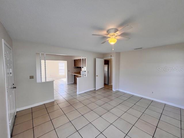 An open-concept living area features light-colored tile flooring, a ceiling fan, and a kitchen pass-through — 8518 N LYNN AVENUE, TAMPA, FL
