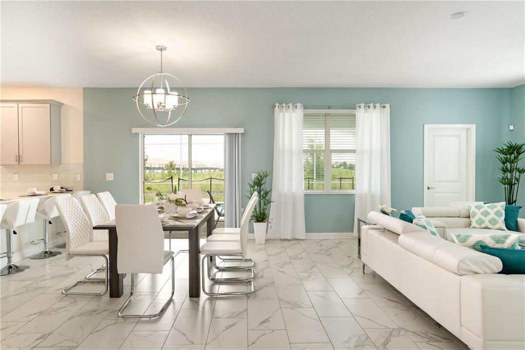 A dining area and living room feature light blue walls, white tile floors, and furniture — 1520 MAIDSTONE COURT, CHAMPIONS GATE, FL
