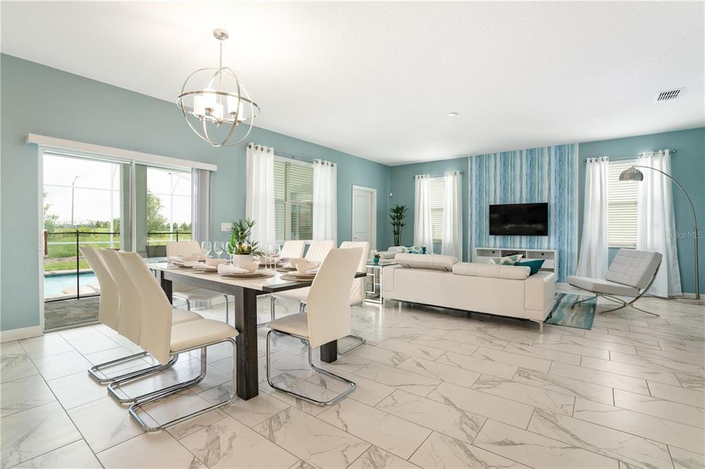 An open-concept living and dining area features light blue walls, white tile floors, and a pool view — 1520 MAIDSTONE COURT, CHAMPIONS GATE, FL