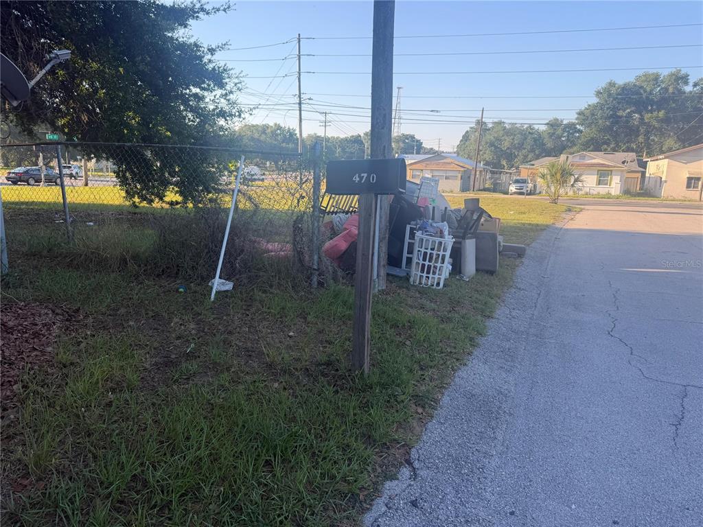 A mailbox labeled 470 stands near a pile of discarded items beside a chain-link fence — 470 S EAST AVENUE, BARTOW, FL