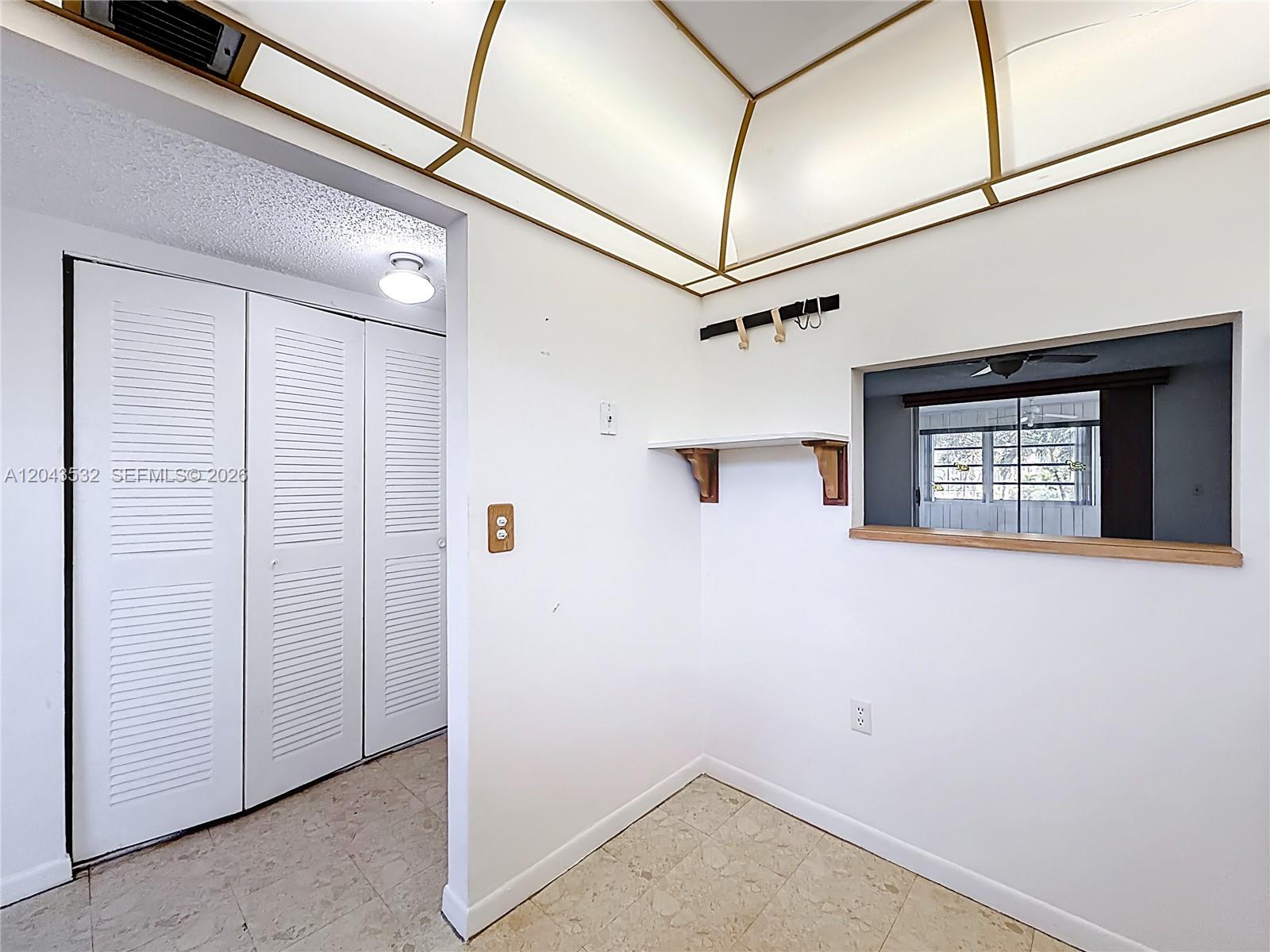 A white room features a pass-through window, a small wall shelf, and louvered closet doors — 6750 Royal Palm Blvd # 209E, Margate FL 33063, MARGATE, FL