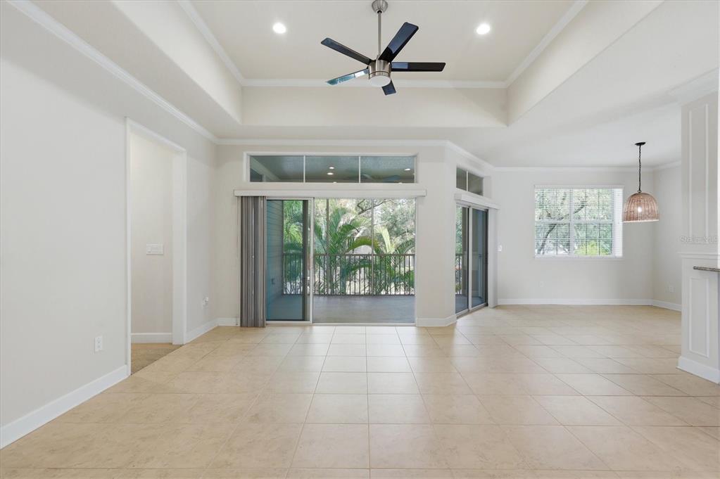 A living room with tile floors, a tray ceiling, a ceiling fan, and sliding glass doors — 7930 TYBEE COURT UNIT 7930, UNIVERSITY PARK, FL