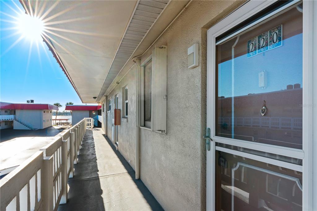 An outdoor balcony walkway leads to a door marked 220 with a view of water — 2901 N HALIFAX AVENUE UNIT 220, DAYTONA BEACH, FL