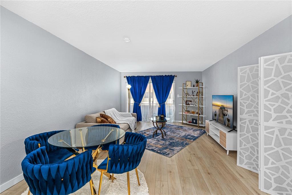 A living and dining area features blue velvet chairs, a glass table, and blue curtains — 2901 N HALIFAX AVENUE UNIT 220, DAYTONA BEACH, FL