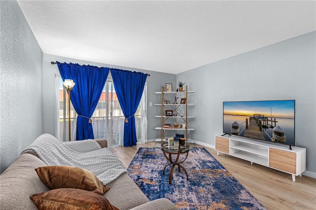A living room features a sofa, a television on a media console, and blue curtains — 2901 N HALIFAX AVENUE UNIT 220, DAYTONA BEACH, FL