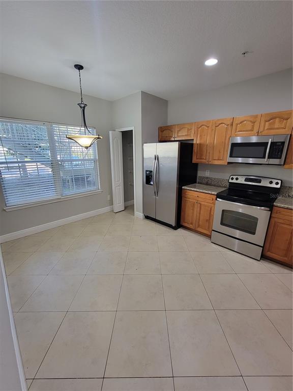A kitchen with light wood cabinets, stainless steel appliances, and beige tile flooring — 3717 S LAKE ORLANDO PARKWAY UNIT 7, ORLANDO, FL