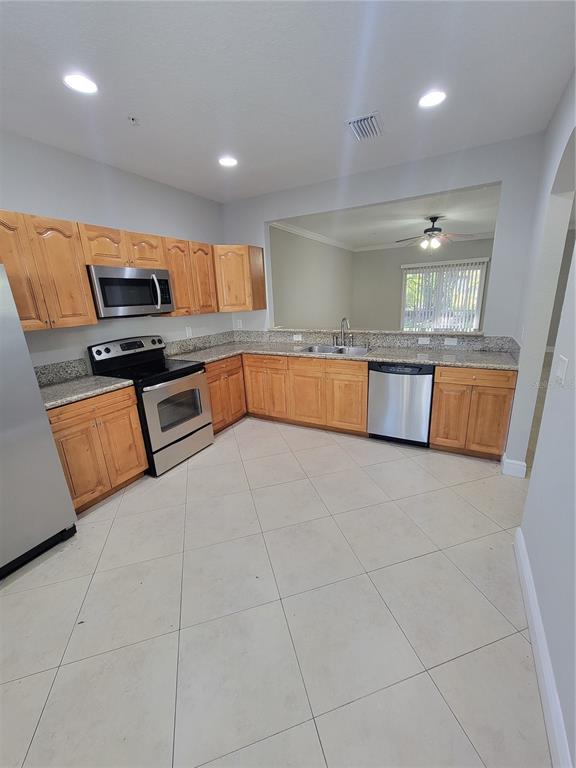 A kitchen features light wood cabinets, granite countertops, stainless steel appliances, and tile flooring — 3717 S LAKE ORLANDO PARKWAY UNIT 7, ORLANDO, FL