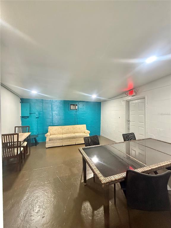 A basement room features a teal painted wall, a beige sofa, and two dining tables — 840 16TH STREET S, ST PETERSBURG, FL
