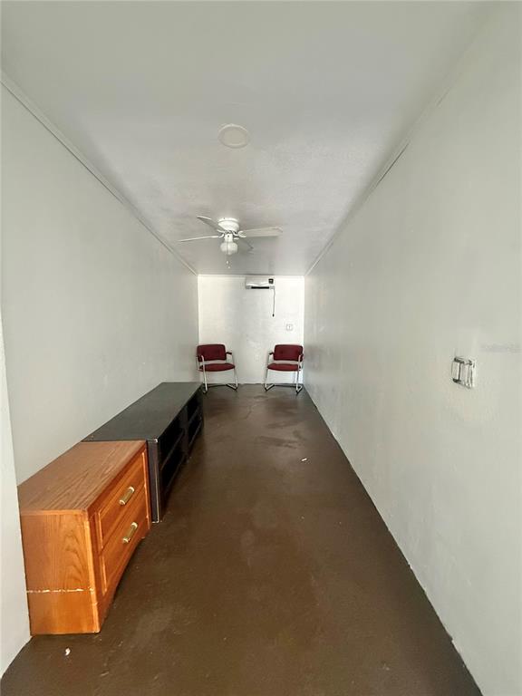 A narrow, sparsely furnished room features a wooden dresser, two chairs, and a ceiling fan — 840 16TH STREET S, ST PETERSBURG, FL