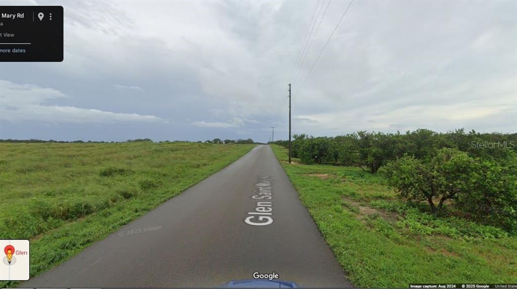 A paved road runs between an open grassy field and a grove of trees — GLENN ST MARY ROAD, LAKE WALES, FL