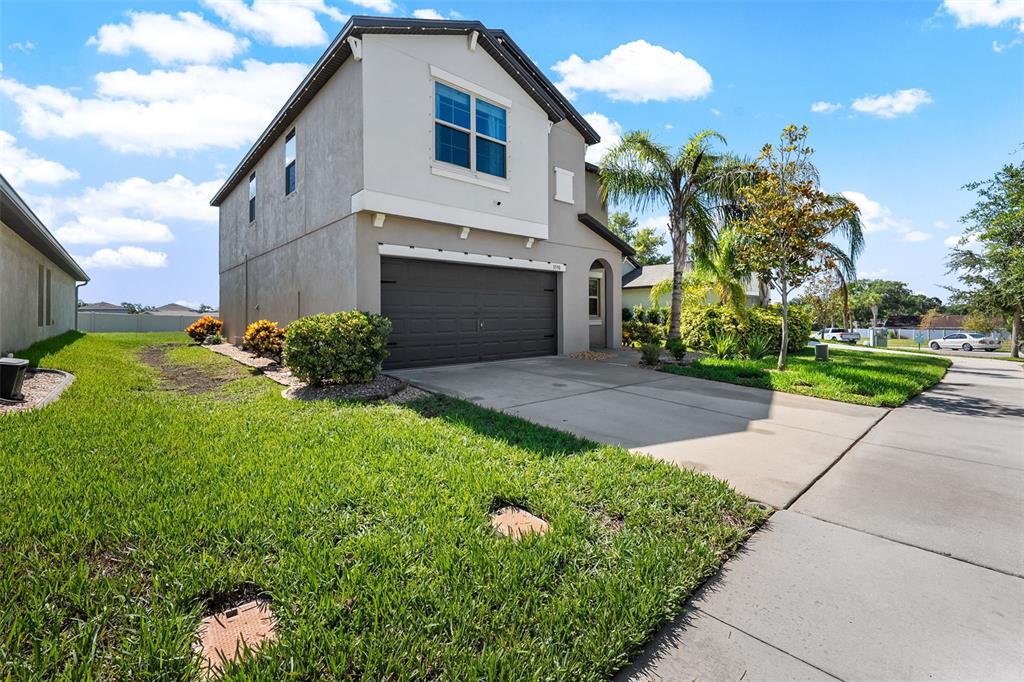 A two-story house with a gray stucco exterior, a dark garage door, and a driveway — 3590 HANOVER DRIVE, NEW PORT RICHEY, FL