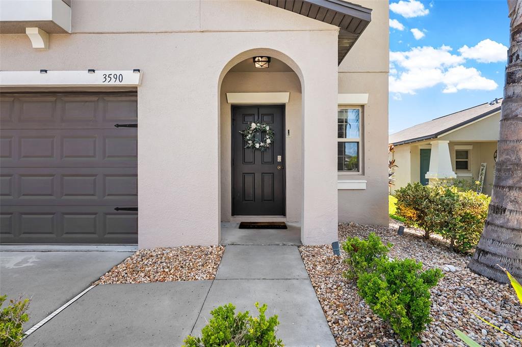 The exterior of a house features a dark front door, a garage, and landscaped gravel — 3590 HANOVER DRIVE, NEW PORT RICHEY, FL