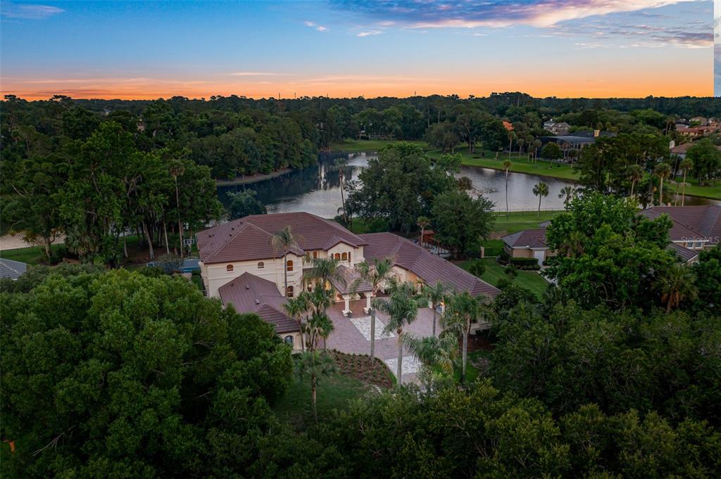 An aerial view shows a large house with a tiled roof near a lake — 3147 TALA LOOP, LONGWOOD, FL
