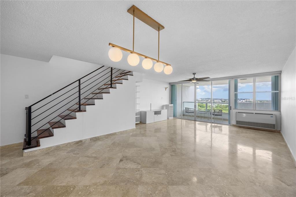 A spacious living room features marble floors, a modern staircase, and a large balcony with views — 146 Ave Santa Ana BOSQUE DE LA VILLA DE TORRIMAR UNIT C-PH-D, GUAYNABO, PR