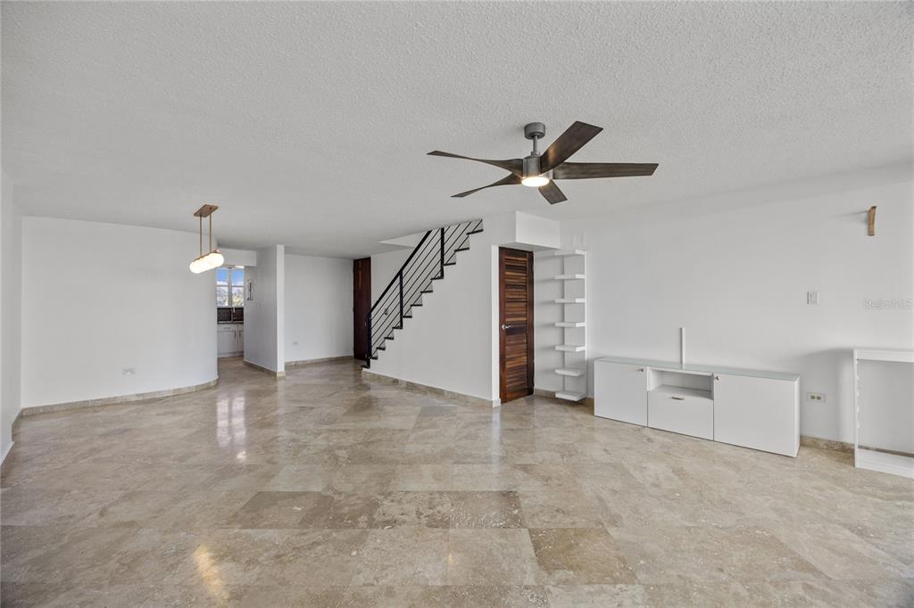 An open living area features stone tile flooring, a staircase with black railings, and a ceiling fan — 146 Ave Santa Ana BOSQUE DE LA VILLA DE TORRIMAR UNIT C-PH-D, GUAYNABO, PR
