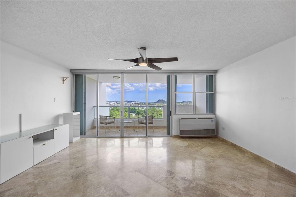 A living room with marble floors, a ceiling fan, and a balcony with mountain views — 146 Ave Santa Ana BOSQUE DE LA VILLA DE TORRIMAR UNIT C-PH-D, GUAYNABO, PR