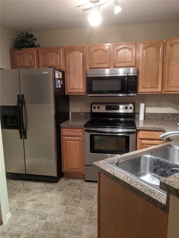 A kitchen features stainless steel appliances, light wood cabinets, and speckled laminate countertops — 3705 SW 27TH STREET UNIT 811, GAINESVILLE, FL