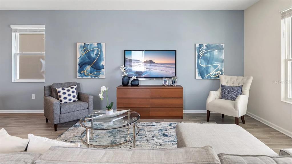 A living room features a television on a wooden dresser between two chairs and artwork — 2401 VOLUNTEER AVENUE, KISSIMMEE, FL