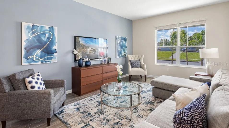 A living room features a gray accent wall, a television, a sofa, and an armchair — 2401 VOLUNTEER AVENUE, KISSIMMEE, FL