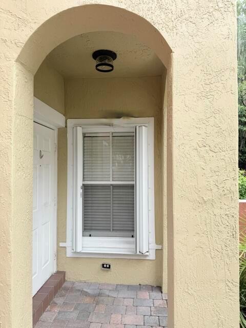 A covered entryway features a white door, a window with shutters, and a paved floor — 3126 Merrick Terrace # 1801, Margate FL 33063, MARGATE, FL
