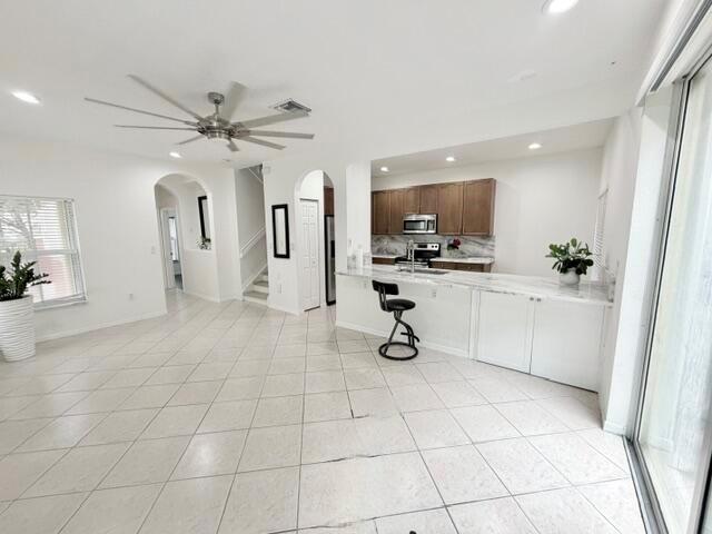 An open-concept kitchen and living area features white tile floors and a breakfast bar — 3126 Merrick Terrace # 1801, Margate FL 33063, MARGATE, FL