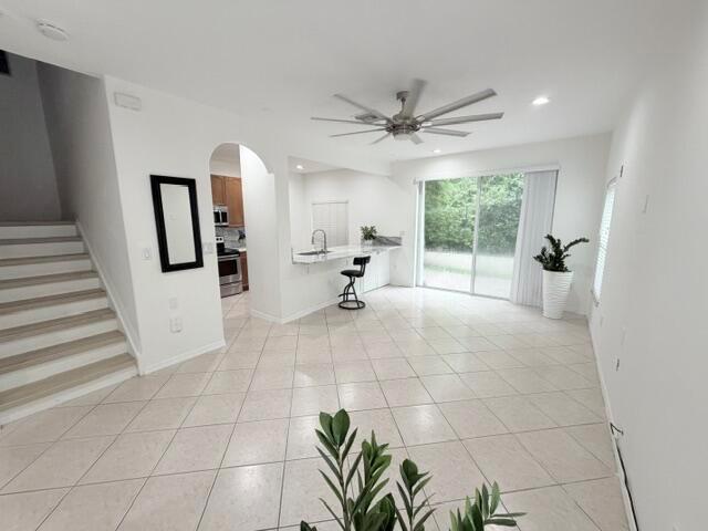 An open-concept living area features tile flooring, a kitchen with a breakfast bar, and stairs — 3126 Merrick Terrace # 1801, Margate FL 33063, MARGATE, FL