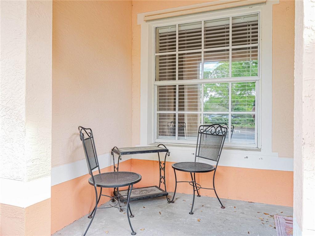 A covered porch features two metal chairs and a small table in front of a window — 2288 57th Circle # 2288, Vero Beach FL 32966, VERO BEACH, FL